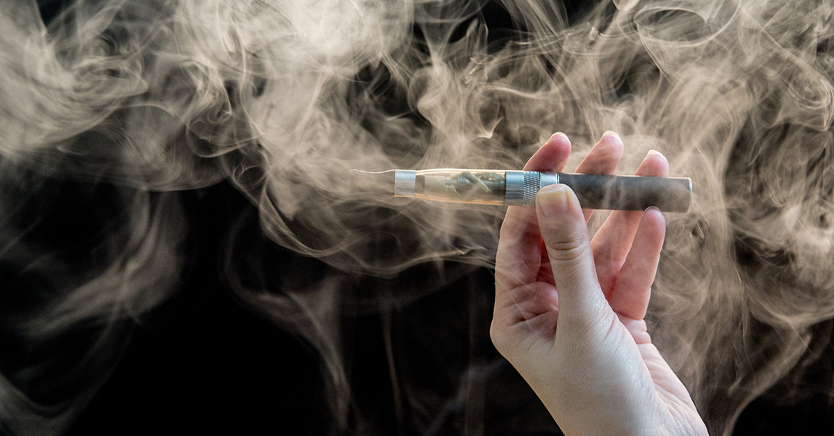 woman smoking electronic cigarette on background